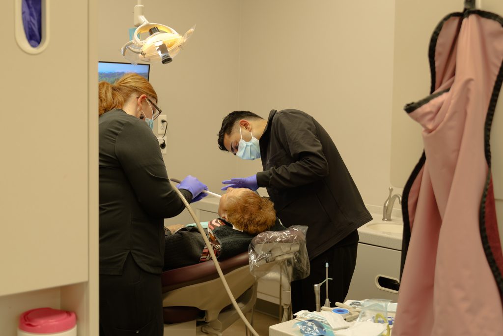 Dentist, Dr. Adeeb Haque and assistant providing gentle dental care to a female senior patient at Maple Dentistry